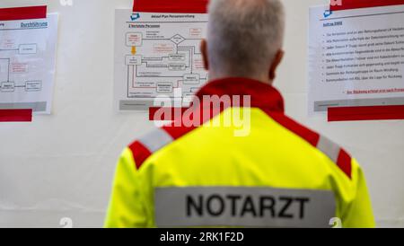 PRODUCTION - 23 August 2023, Lower Saxony, Dethlingen: An emergency doctor looks at the 'Ablauf Plan Personenrettung' at the salvage hall of Dethlinger Teich. Chemical weapons from the Wehrmacht are now to be recovered from the Dethlingen pond. The pond was filled in after the Second World War. More than 100,000 different weapons are said to be in the ten to twelve meter deep pond. An investigation of a neighboring groundwater body had revealed massive contamination with explosive ordnance degradation products. During the subsequent reconnaissance of the pond between September 2019 and April 2 Stock Photo