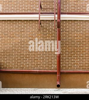 red brick wall of renovated old industrial building with newly installed drainpipe Stock Photo