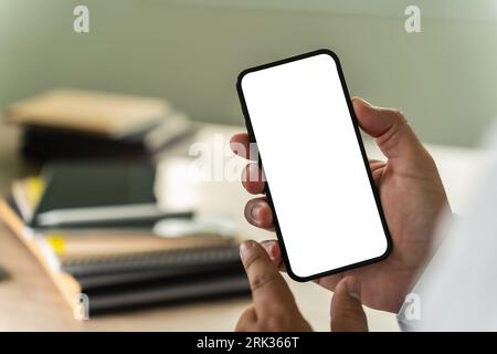 uomo d'affari che dispone di uno smartphone mobile con schermo vuoto per la comunicazione di messaggi di testo pubblicitari in background sul posto di lavoro Foto Stock