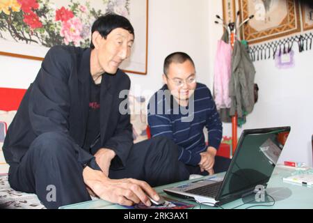 Bildnummer: 53401062 Datum: 21.09.2009 Copyright: imago/Xinhua -- CHIFENG, (Xinhua) -- 2,36 metri di altezza il mandriano cinese Bao Xishun (L), l'uomo più alto del mondo precedente, sfoglia le notizie online a casa, nella città di Chifeng, nella regione autonoma della Mongolia interna, 21 settembre 2009. Il 16 settembre il Guinness dei primati ha annunciato che il 27enne turco Sultan Kosen, con la sua altezza convalidata a 2,465 metri, prende il titolo di Bao Xishun, l'uomo più alto del mondo. Il disco di Kosen è stato svelato per celebrare il lancio dell'edizione 2010 del Guinness World Records, ora nella sua Foto Stock
