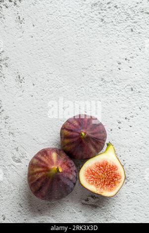 Vista dei fichi organici interi e tagliati su tavola di pietra Foto Stock