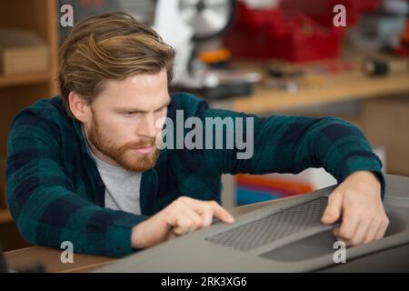 il meccanico ispeziona il paraurti dell'auto danneggiato Foto Stock