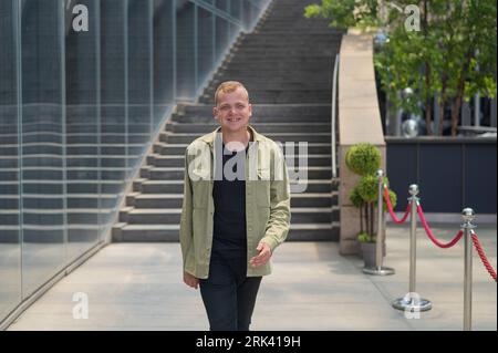 Joyful caucasian Guy passa davanti a un edificio commerciale. Foto Stock