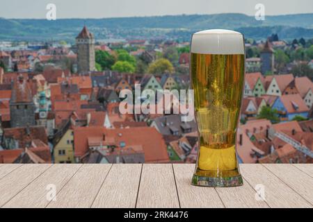 Glass of light beer on Rothenburg old town background. View from above with city wall and towers in Rothenburg ob der Tauber, Germany. Foto Stock