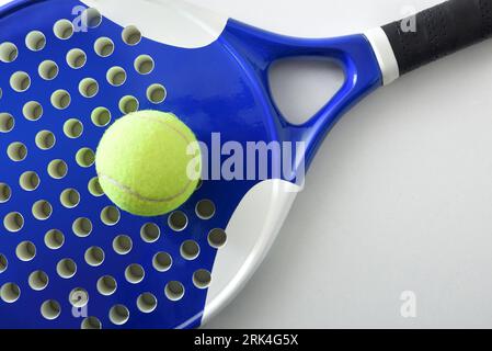 Dettaglio di racchetta da paddle tennis bianca e nera e palla su un tavolo bianco. Vista dall'alto. Foto Stock