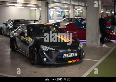 Vista frontale di un'auto sportiva giapponese Toyota GT86 nera con strisce colorate parcheggiata nel parcheggio sotterraneo Foto Stock