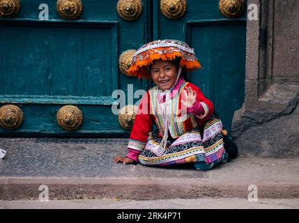 A Latin American girl in traditional Peruvian dress, sitting outdoors Stock Photo