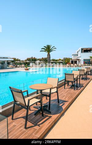 Kos, Grecia - 7 maggio 2023: Tavoli e sedie da caffè vicino alla piscina nell'hotel greco resort sull'isola di Kos. Grecia Foto Stock