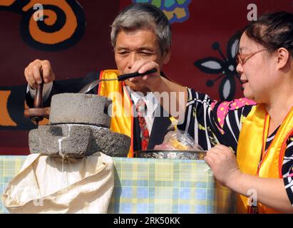 Bildnummer: 53684978  Datum: 23.12.2009  Copyright: imago/Xinhua (091223) -- TAIPEI, Dec. 23, 2009 (Xinhua) -- demonstrate grinding glutinous rice with an ancient kitchenware in an activity of making sweet soup dumplings at a middle school in Taipei, southeast China s Taiwan. Several thousand teachers, students and students parents gathered at the school to observe a traditional custom of making sweet dumplings at the Winter Solstice. (Xinhua/Wu Ching-teng) (px) (6)CHINA-TAIPEI-SWEET DUMPLING-WINTER SOLSTICE(CN) PUBLICATIONxNOTxINxCHN Sonnenwende Wintersonnenwende kbdig xkg 2009 quer premiumd Stock Photo