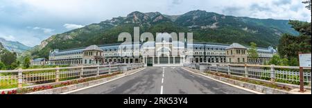 A tranquil scene of an open road with a building at the end of it, with mountains in the background Stock Photo