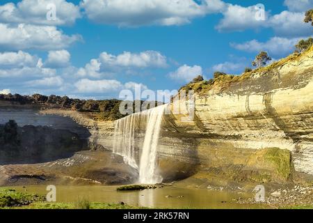 An awe-inspiring, cascading waterfall flowing down a river framed by lush, green vegetation Stock Photo