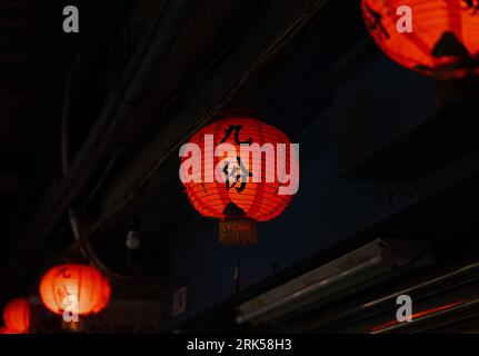 Un basso angolo di lanterne cinesi sospese dal soffitto di un edificio di stile Asiatico Foto Stock