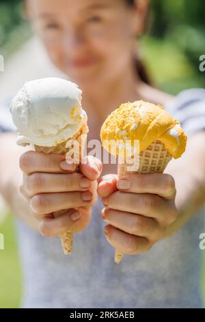 Le mani delle donne tengono un gelato rinfrescante in coni di waffle con un pizzico di saporito sapore di limone Foto Stock