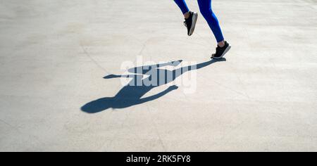 l'ombra di una donna atleta che fa jogger in strada Foto Stock