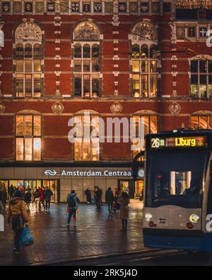 Amsterdam, Netherlands - November 27 2022: A tram stops passes by Centraal Station in Amsterdam on a wet November evening. Stock Photo