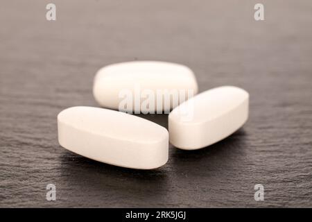 Several medical pills on slate stone, macro. Stock Photo