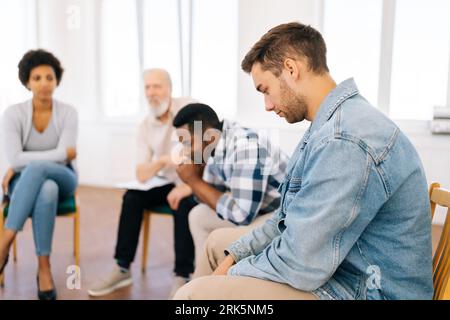 Vista di messa a fuoco selettiva laterale dei reclami parlanti di uomini neri pensivi discutere problemi di vita lutto nella sessione di terapia di gruppo. Concetto di salute mentale Foto Stock
