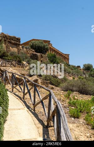 Un sentiero idilliaco che si snoda attraverso antiche rovine e lussureggiante vegetazione fino al magnifico Tempio della Concordia ad Agrigento, Italia Foto Stock