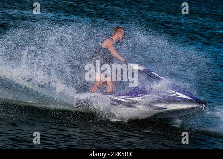 Un uomo è in moto d'acqua attraverso un sereno specchio d'acqua Foto Stock