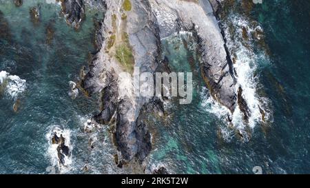 Una vista aerea dall'alto verso il basso delle aspre scogliere costiere con acque cristalline Foto Stock