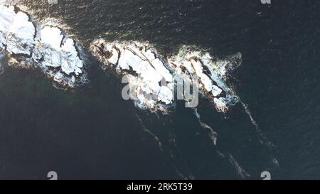 Una vista aerea dall'alto verso il basso delle aspre scogliere costiere con acque cristalline Foto Stock