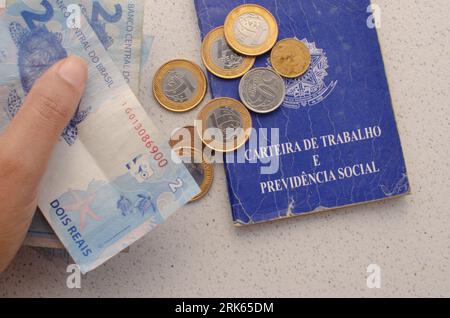 Scheda di lavoro per il Brasile. Traduzione - Repubblica Federativa del Brasile, Ministero del lavoro. Scheda di lavoro per il Brasile con soldi sul lato. simboleggiando l'importanza Foto Stock