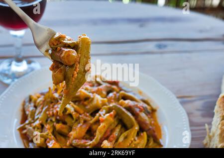 Cucina mediterranea estiva, okra o mpamies in Grecia, con salsa in pentola Foto Stock