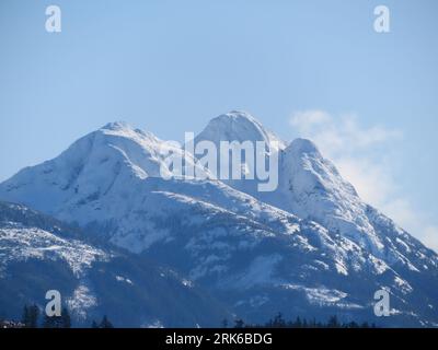 Una vista panoramica di una montagna innevata sotto un cielo blu. Foto Stock