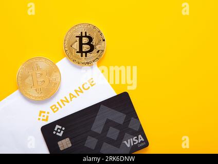 LONDON,UK - NOVEMBER 05, 2022: Binance visa credit card with bitcoins on yellow background with invitation letter. Top view. Stock Photo