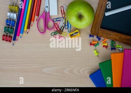top view of light wooden desk with notebooks and colorful paints other school supplies Foto Stock