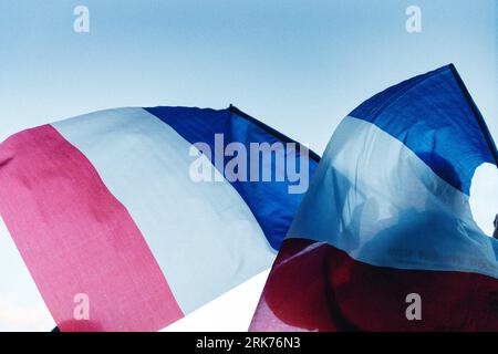 Le due bandiere francesi che soffiano al vento sullo sfondo di un cielo blu. Foto Stock