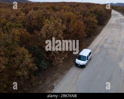 An aerial view of a white minivan parked on the edge of a room in autumn Stock Photo