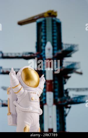 Un astronauta giocattolo si trova sullo sfondo di un razzo che decolla da una rampa di lancio. Foto Stock