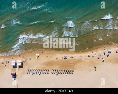 vista aerea spettacolare di una spiaggia in estate con bagnanti, pedalò e ombrelloni in paglia a noleggio, rampa di accesso per disabili e torre di osservazione Foto Stock