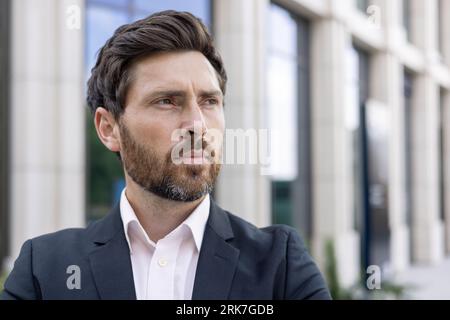 Portrait of a young businessman, director, lawyer man in a business suit standing outside and looking seriously to the side. Close-up photo. Foto Stock