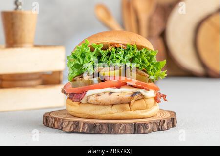 Un delizioso hamburger di pollo con pancetta croccante, pomodori succosi, lattuga fresca e jalapeno. Foto Stock