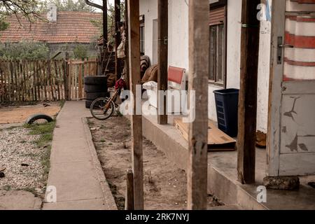 Una vecchia casa con un esterno intemprato e una bicicletta appoggiata contro la parete laterale Foto Stock