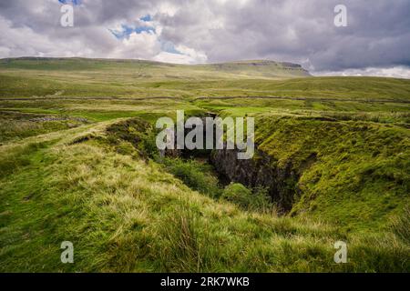 View along the full length of Hull Pot. A collapsed cavern near Penyghent in the Yorkshire Dales.Pen-Y-Ghent is the mountain in the distance. Stock Photo