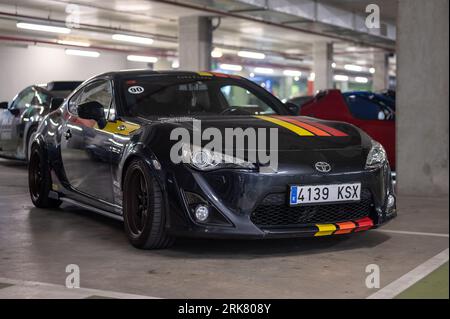 Vista frontale di un'auto sportiva giapponese Toyota GT86 nera con strisce colorate parcheggiata nel parcheggio sotterraneo Foto Stock