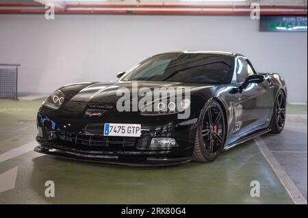 Vista frontale di una classica auto sportiva americana, la Chevrolet Corvette C6 Z51 nera parcheggiata in un parcheggio sotterraneo Foto Stock