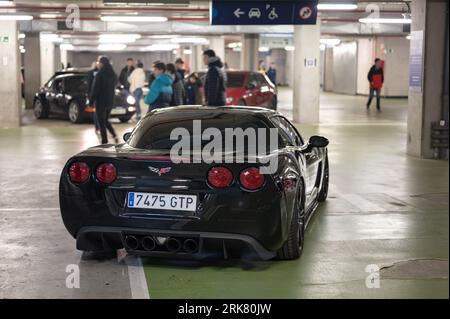 Vista posteriore di una classica auto sportiva americana, la Chevrolet Corvette C6 Z51 nera parcheggiata in un parcheggio sotterraneo Foto Stock