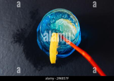 A high-resolution close-up image of a vibrant blue beverage filling a transparent cup, with a colorful straw protruding from the top Stock Photo