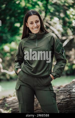 Un allegro soldato in uniforme militare verde si sta diffondendo positivamente mentre si trova in un campo Foto Stock