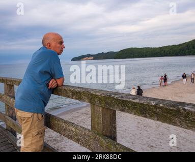 0 y.o. man looks at the scenery from a pier on a beach by the baltic coast in Germany Stock Photo