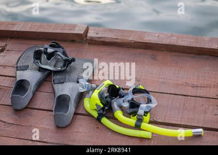 Set completo di attrezzature per immersioni subacquee con attenzione selettiva al molo di legno. Alette, misuratore di profondità, regolatore bilanciato, generatore di gas, maschera da immersione e snorkeling. Foto Stock