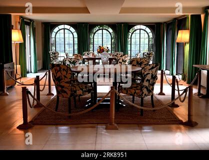 Uno scatto interno di una lussuosa sala da pranzo con un tavolo in legno con sei sedie disposte intorno e un tappeto a motivi geometrici sotto Foto Stock