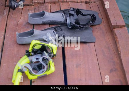 Set completo di attrezzature per immersioni subacquee con attenzione selettiva al molo di legno. Alette, misuratore di profondità, regolatore bilanciato, generatore di gas, maschera da immersione e snorkeling. Foto Stock