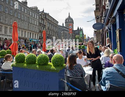 Royal Mile, Edimburgo, Scozia, Regno Unito. 24 agosto 2023. Ultimo giovedì di sole per gli artisti di strada e coloro che cercano intrattenimento sulla High Street della capitale. Le strade sono più tranquille di quanto ci si aspetterebbe, consentendo più spazio per la circolazione delle persone. Temperatura di circa 18 gradi centigradi. Nella foto: Gordon's Trattoria fa buoni affari al sole. Credito: Notizie dal vivo Archwhite/alamy. Foto Stock