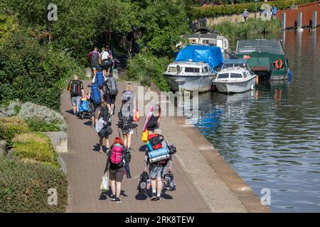 Giovani che camminano lungo la riva del fiume Tamigi fino a Reading Festival, Reading, Berkshire, Inghilterra, Regno Unito, Europa Foto Stock