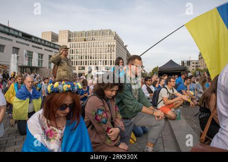 Gli ucraini si riunirono alla porta di Brandeburgo a Berlino il 24 agosto 2023, per celebrare il giorno dell'indipendenza dell'Ucraina. Ma questa non era una festa ordinaria. La folla, un mare di girasoli, bandiere, striscioni e abiti tradizionali ucraini, è arrivata con un messaggio di memoria e resilienza. In un gesto simbolico, i partecipanti tenevano degli specchi, 503 in totale, ciascuno che rifletteva il volto di un bambino perso nella guerra russa contro l'Ucraina. Sotto il sole che tramonta, gli specchi sono serviti come un ricordo inquietante dei 503 bambini ucraini le cui vite sono state bruscamente e spietatamente prese nel conflitto. Ucraino Foto Stock